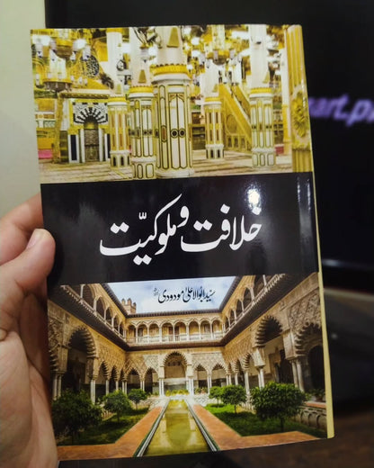 Book cover with mosque illustration and Urdu title, held in hand