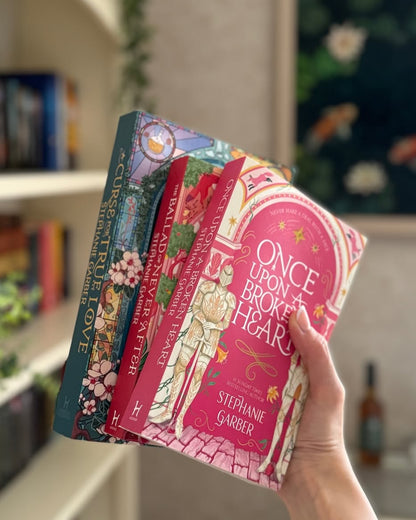 Stack of 3 paperback fantasy novels held in hand, featuring Once Upon a Broken Heart cover