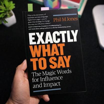 Handheld black book with orange 'EXACTLY WHAT TO SAY' lettering and 'Magic Words' subtitle