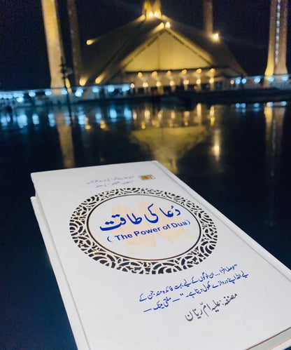 Urdu edition book cover angled view with blue title inside gold decorative ring